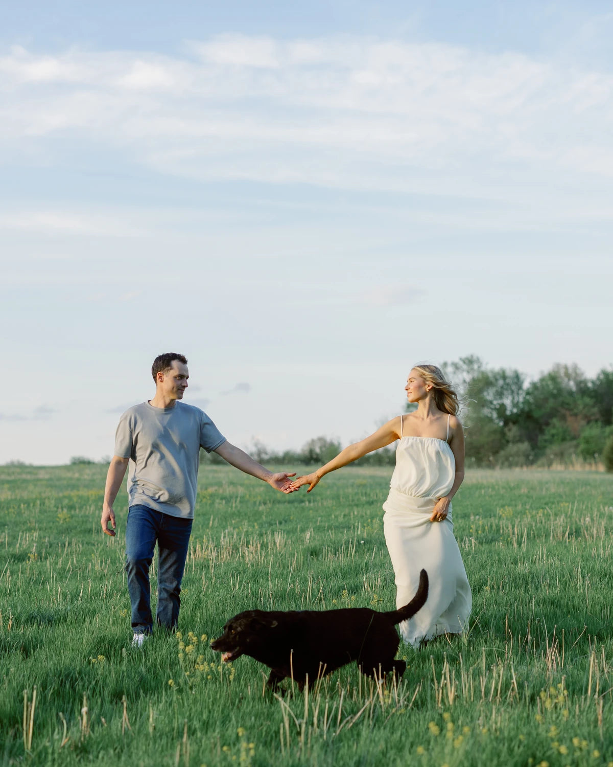 The family behind Dog Treat Naturals walking through a Midwest field with their dog at golden hour